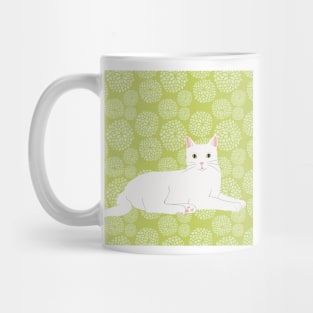 The cute and alert white cat is waiting and watching you in a fresh spring green meadow Mug